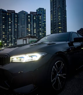 a black bmw car parked in front of a cityscapeople