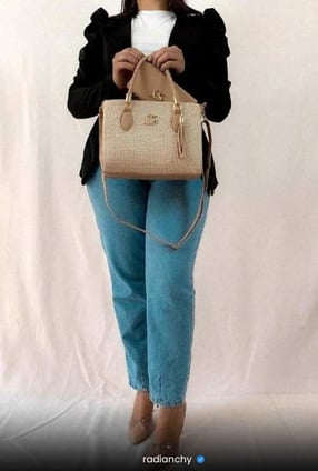 a woman in jeans and a white shirt is holding a purse