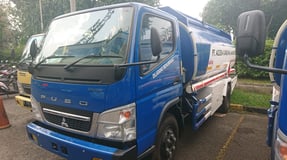 a blue truck with a white truck behind it