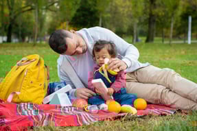 a man and a little girl sitting on a blanket