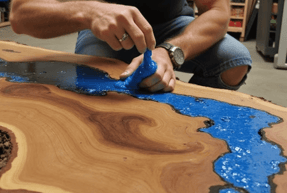 Blue resin epoxy being poured in a live edge wood table with resin epoxy