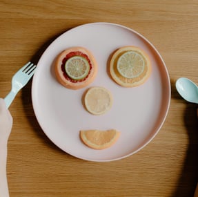 a child's face made of fruit on a plate