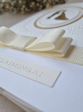 a wedding card with a white bow, money envelope