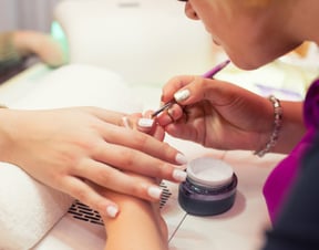 A lady receiving a nail treatment from a meticulous manicurist