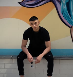 a man sitting on a bench in front of a mural of a woman