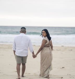 a couple holding hands and walking on the beach