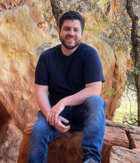 Christopher Carpenter sitting on a rock formation in the Utah mountains.