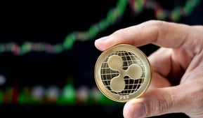 ripple xrp token in someones hands with charts in background