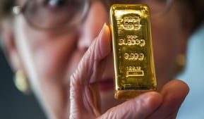 elderly woman holding a gold bar in her hands