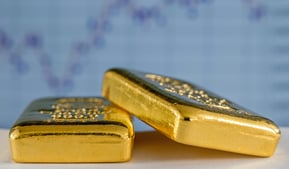 gold bullion bars on flat surface with charts in background