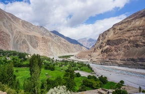 a valley with a river and mountains in the background