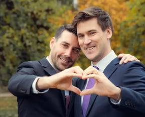 "Pareja gay casada en España, formando un corazón con las manos y celebrando su amor y boda."