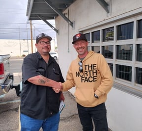 two men shaking hands in front of a building