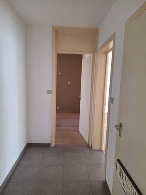 Vue d'un couloir avec des portes beiges avant transformation