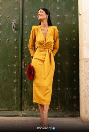 a woman in a yellow dress standing in front of a green door