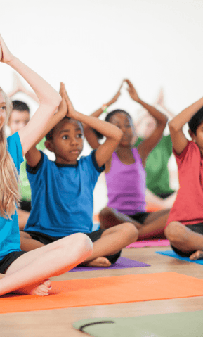 Children group yoga with rainbow colored mats