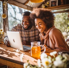a man and woman sitting at a table with a laptop