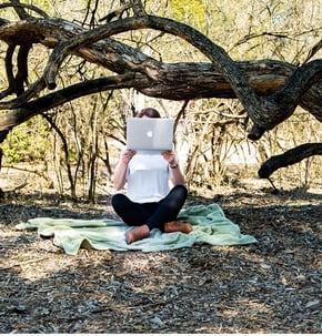 girl with laptop in woods hiding face