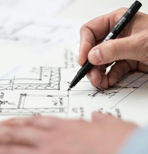 una mano disegna un progetto con un pennarello nero