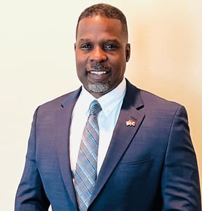 Dr. Marlon Ware standing in blue suit with blue striped tie