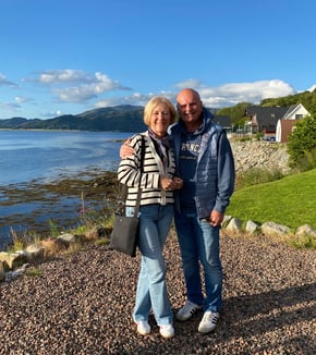 a man and woman standing in front of a lake