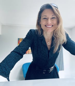 Caroline Muldoon, menopause coach, leaning on desk in business attire