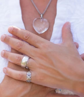 lady's hands clasped over her chest in a peaceful way she wears a white blouse and jewellry