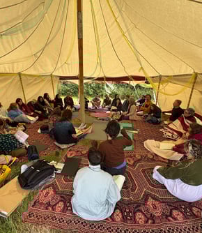 30 people in sharing circle in large tent