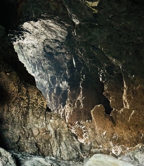 Photo of a huge cave with light at the end of the tunnel, Merlins cave Cornwall