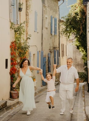 Parents jouant avec leur enfant dans une ruelle de village – séance photo de famille naturelle Gard