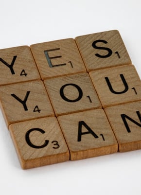 9 wooden Scrabble tiles laid in a square. Spell Yes You Can