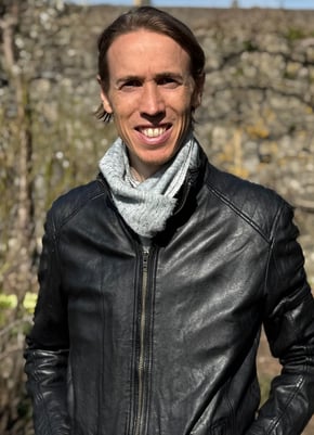 Photo of Chris, Wellbeing and health coach South Wales, standing outside in the sun wearing leather jacket