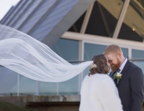 Bride and groom standing face to face, her veil flowing behind. Canberra wedding photographer.