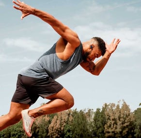 a man in a gray tank top and shorts is running
