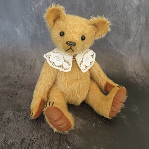 a handmade teddy bear wearing a lace collar