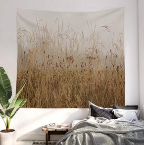 Wall tapestry hanging on a bedroom wall with bed underneath it and bedding on bed