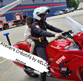 un enfant des ateliers créatifs sur une moto de pompier au GSPM