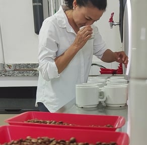 a woman in a white shirt and red trays of chocolate covered with chocolate