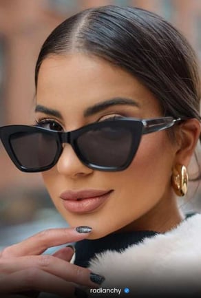a woman with a cat eye sunglasses and a fur coat