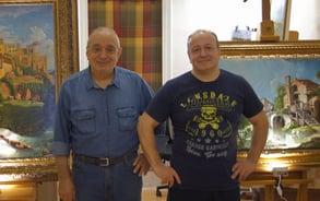 two men standing next to each other in front of a painting