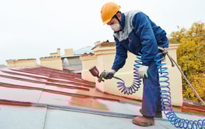 a man in a helmet painting a roof