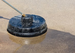 a person using a pressure to clean a driveway