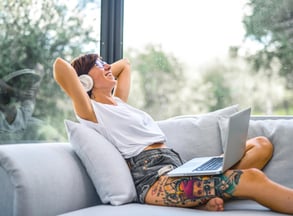 a woman sitting on a couch with her laptop. She is practicing English with music