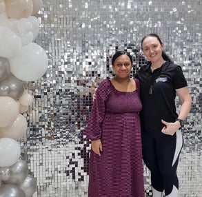 Carly from SweetAz Co. and Denise's sister in front of the silver shimmer wall hired for her graduation in Brisbane