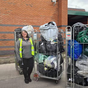 female volunteer standing near three cages of donated goods