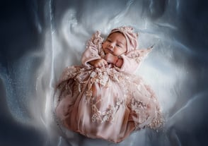 Neonata in abito rosa fotografata da Gaudife a Bologna – fotografia newborn emozionale con luce naturale e stile raffinato