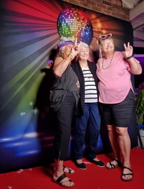 3 ladies striking a pose in the digital open air photo booth in front of a disco ball backdrop for Chrissie's MS fundraising 