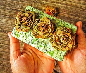 Small green recycle paper storage with three natural yellow rose carried with hand