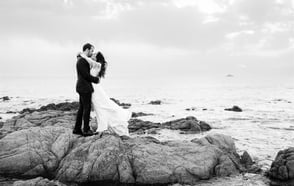 Black and white editorial fine art photo of bride and groom kissing by the sea in South of France