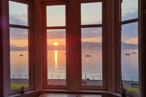 The window at Gourock Seaview Holiday Let with a view of the sun setting over the water